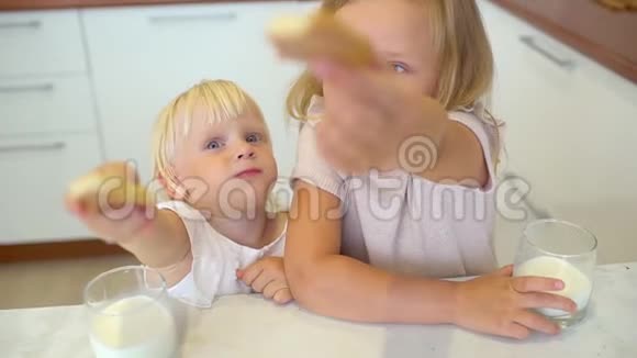 两个姐妹小女孩坐在桌子旁享受着家做的饼干把它们灌进一杯视频的预览图