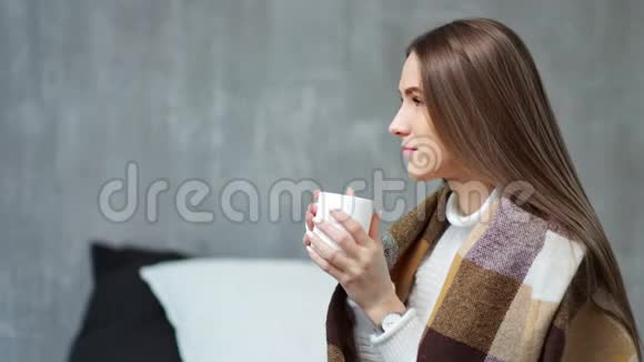 中等特写镜头微笑的年轻欧洲女孩裹着温暖的格子在舒适的家做梦视频的预览图