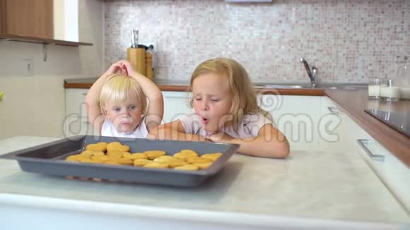 你的家人妈妈在桌子上放了一杯牛奶给两个妹妹小女孩孩子们吃牛奶和饼干视频的预览图