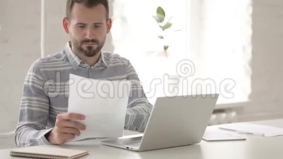 休闲青年在笔记本电脑上做纸工和打字视频的预览图