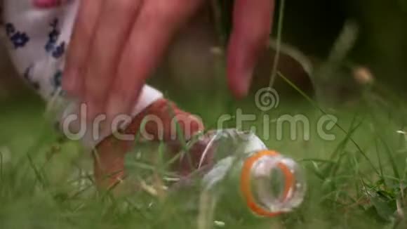 幼儿手从绿草地上拿塑料瓶快关门垃圾收集环境意识视频的预览图