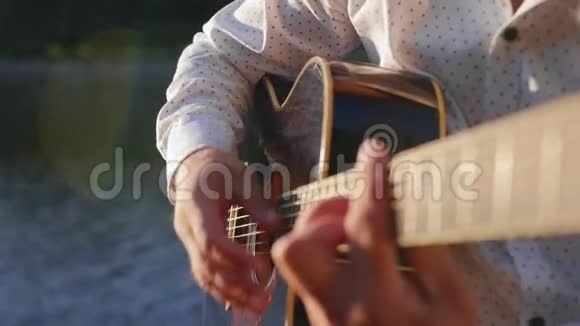 人弹吉他对着湖面唱歌吉他手触摸吉他弦近距离射击视频的预览图