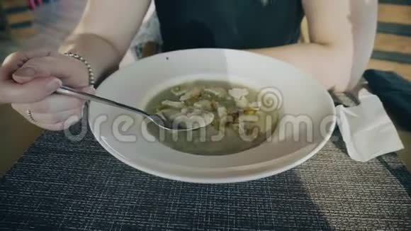 女孩坐在餐厅的桌子上吃着汤泥白色的盘子不错的待遇镜头拍摄一张桌子一个盘子和一个杯子视频的预览图
