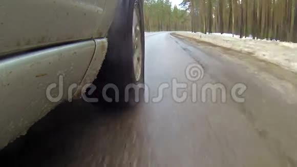 在森林的冬季道路上行驶时摄像机安装在汽车上它会变成雪水溅到镜头上视频的预览图