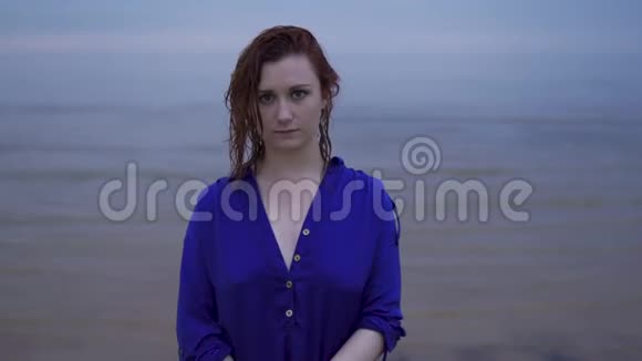 特写一幅年轻红发女子的肖像她穿着一件蓝色连衣裙头发湿漉漉的带着生动的洋红色的忧郁的夕阳视频的预览图