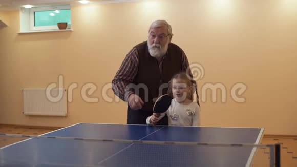 祖父教孙女打乒乓球站在她身边小女孩把球打掉了休闲视频的预览图