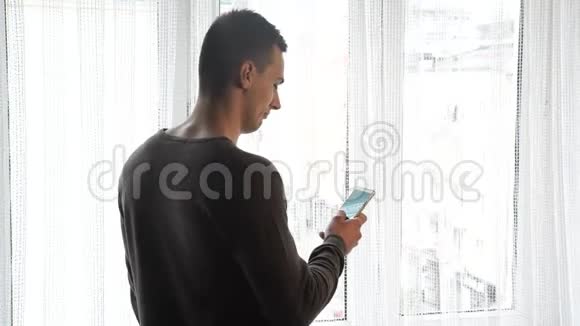 等着看窗外的男人拿着电话视频的预览图