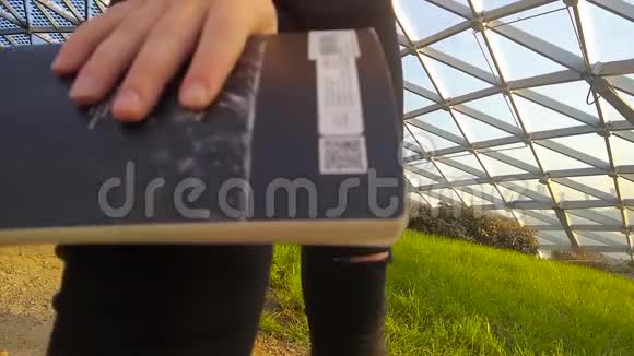 一个拿着笔记本的女孩坐在穹顶下的草坪上视频的预览图