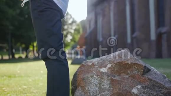 穿着经典衬衫的成年人靠近石头坐在公园里视频的预览图