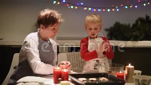 快乐的小男孩和他年轻的祖母在节日期间一起烤饼干圣诞节和新年有孩子视频的预览图