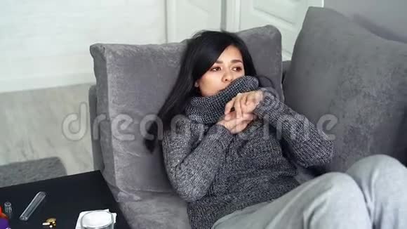 特写女青年测量坐在家里沙发上的温度女人在病毒或感冒时感到不快乐视频的预览图