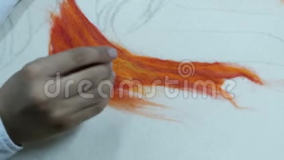 特写镜头一个穿着白色衬衫的少年在橙色干毡上戳了一根针在一张彩色羊毛照片上视频的预览图