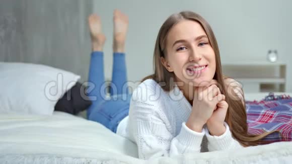 迷人的年轻女子躺在床上微笑着光着脚尽情玩耍视频的预览图