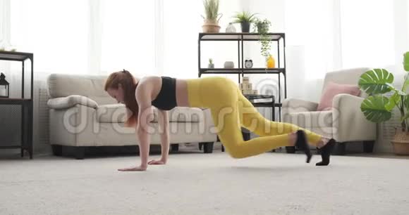 穿运动服装的女人在家做木板运动视频的预览图