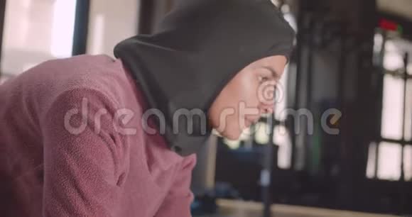 年轻坚定的穆斯林女性戴着头巾在室内健身的特写照片视频的预览图
