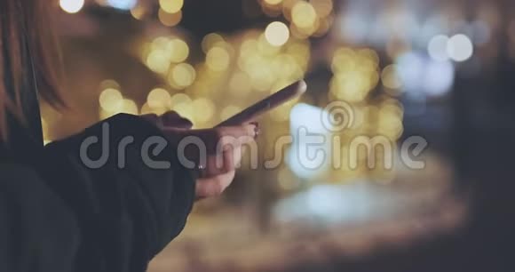 夜间在城市里用手机拍摄女子双手特写镜头视频的预览图