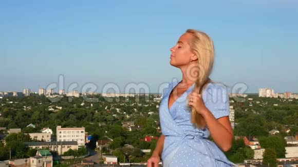 穿着蓝色圆点花裙在屋顶上摆姿势的女孩视频的预览图