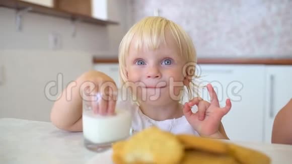 一个金发可爱的小女孩坐在厨房里吃饼干的画像视频的预览图