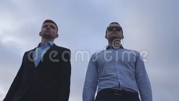 两个年轻的商人在城市里散步背景是蓝天英俊的同事一起上下班视频的预览图