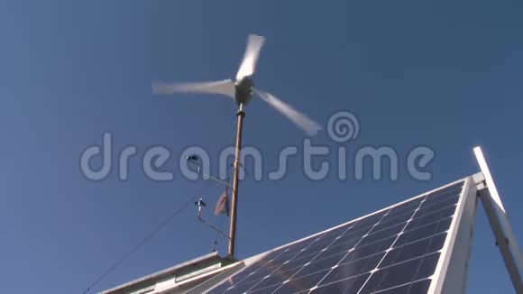 带有蓝天背景太阳能电池板的小型风力涡轮机视频的预览图