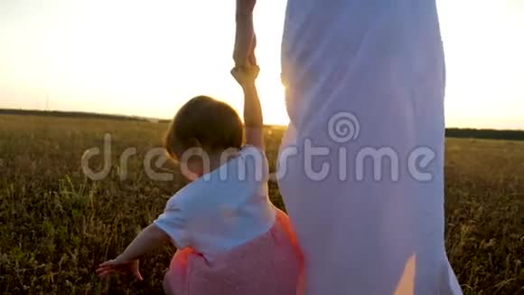 小女孩牵着妈妈手在夕阳的照耀下妈妈和女儿正在明亮的秋天公园里散步视频的预览图