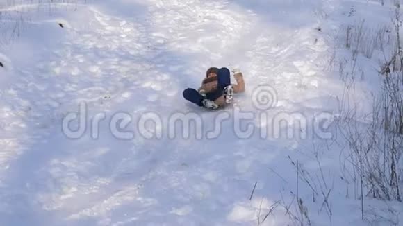 快乐的女孩正在滑下白雪覆盖的雪橇女孩冬天在公园里玩慢动作视频的预览图