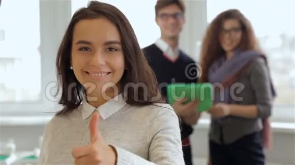 微笑的女孩在男人和女人面前用平板电脑手势良好的品质视频的预览图
