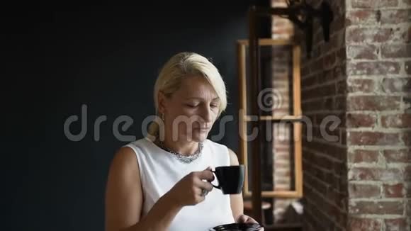 漂亮的高级女人在工作中的午休时间喝咖啡有魅力的成熟女人在家喝咖啡视频的预览图