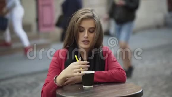 快乐的女孩在街头咖啡馆喝咖啡真诚地微笑4K视频的预览图