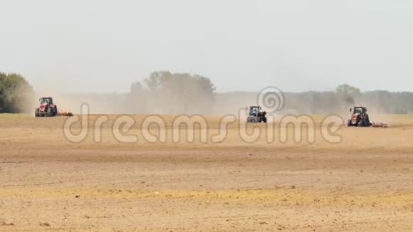 三台拖拉机在松林的背景下制造出一种褐色的尘土飞扬的干旱土壤视频的预览图