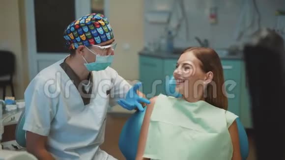 快乐的女性病人和牙医微笑并显示拇指与相机4K视频的预览图