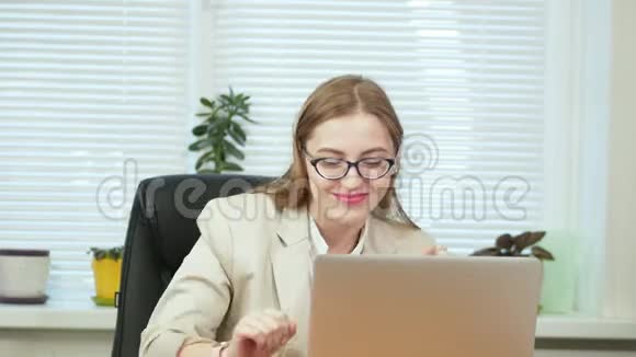 快乐有趣的年轻女士在办公室坐在电脑前跳舞叛逆傻瓜玩得开心视频的预览图