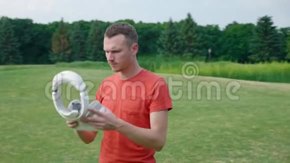 一个男人把VR耳机放在公园的头上环顾四周视频的预览图