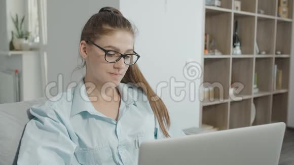 十几岁的女孩在家里用笔记本电脑在社交网络上聊天笑着笑着视频的预览图