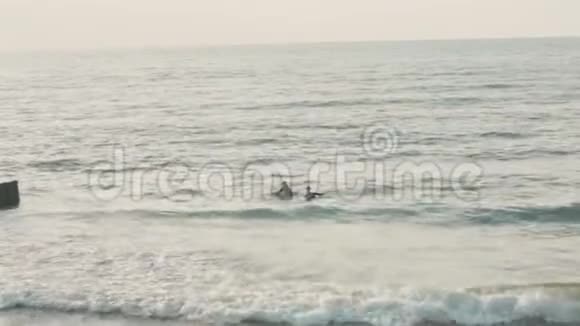 海浪在防波堤上翻滚冲浪者在木板上游泳视频的预览图
