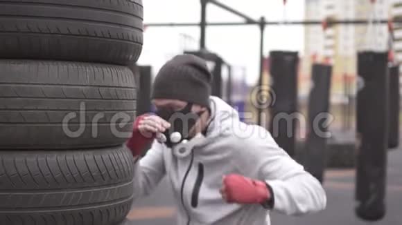 男运动员戴着训练面具和拳击类型的拳击在街头训练场上慢摩视频的预览图