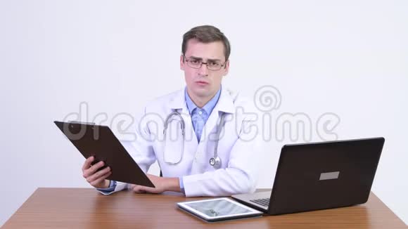 年轻严肃的医生在木桌旁解释一些事情视频的预览图