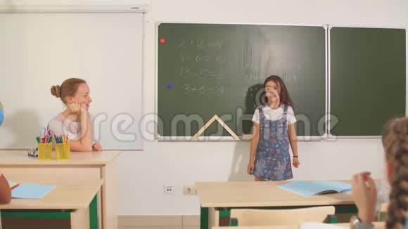 在教室里和老师一起上学黑板旁边的女孩展示她的家庭作业视频的预览图