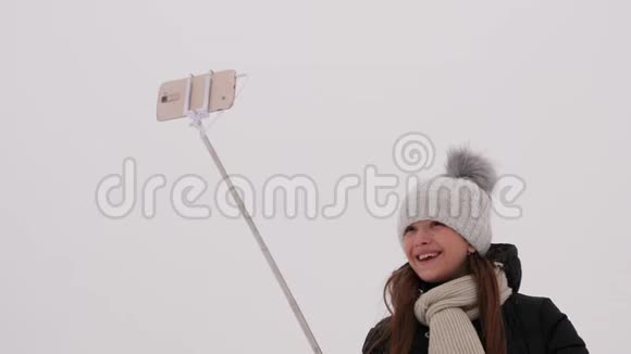 在冬季公园的圣诞节早晨女孩们在智能手机上拍照冬天走在街上的快乐女孩白人视频的预览图