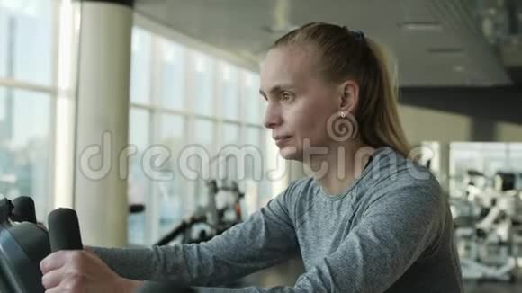 漂亮的中年妇女在健身房骑运动自行车视频的预览图