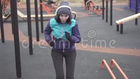 戴着耳机的女运动员在街头操场上锻炼慢悠悠视频的预览图