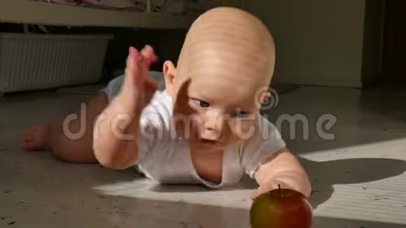六个月大的婴儿躺在地板上伸手要一个红苹果婴儿学会爬行孩子累了把头视频的预览图