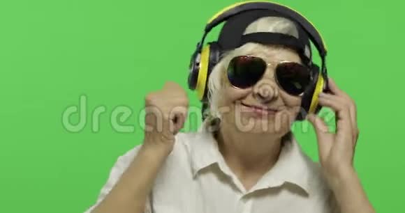 老年妇女用耳机和舞蹈听音乐奶奶铬键视频的预览图