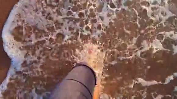 慢动作女孩在海边散步波浪在她脚上翻滚视频的预览图
