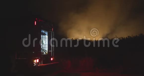开着闪烁灯的消防车森林火灾时在野外焚烧草地背景下的消防车救援和救援视频的预览图