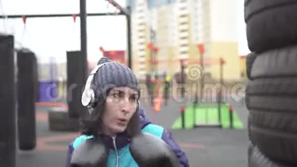 戴拳击手套的女运动员在街头训练场上打梨闭上嘴视频的预览图