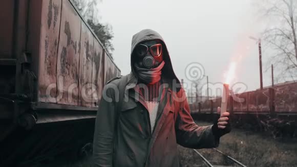 戴防毒面具的人穿过废弃的火车站拿着信号火视频的预览图