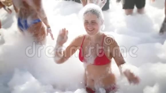 4K慢动作视频欢快的年轻女子穿红色比基尼在海滩上跳舞覆盖着肥皂泡沫快乐的夏天视频的预览图