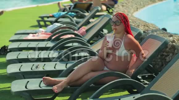 一位年轻女子在游泳池附近的一张躺椅上晒太阳视频的预览图