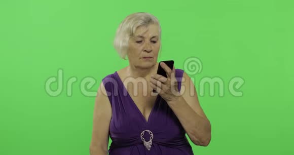 一位老年妇女在智能手机上交谈老奶奶笑了铬键视频的预览图